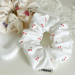 Detail of fabric scrunchies set with red cherry and floral patterns on white tray