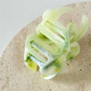 Detail of flower hair claw clip with pale green and white marble acetate texture