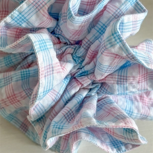Detailed macro view of pink and blue plaid fabric scrunchie with layered ruffle edges