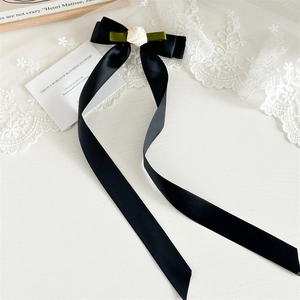 Detailed close-up of a French vintage satin bow hairclip with a delicate white rose