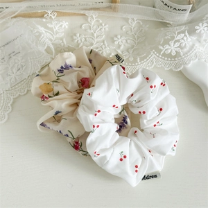 Close-up of floral and cherry pattern fabric scrunchies on a white wooden surface
