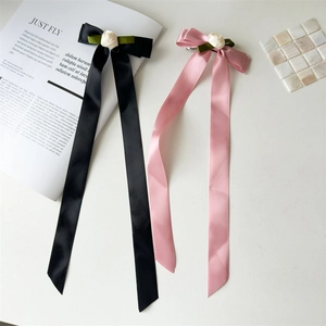 Detail of satin bow hair clips with rose ornaments and long elegant ribbons in black and pink