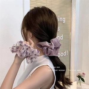 Dettaglio di elastici scrunchie in tulle lavanda a pois con texture soffice e velata