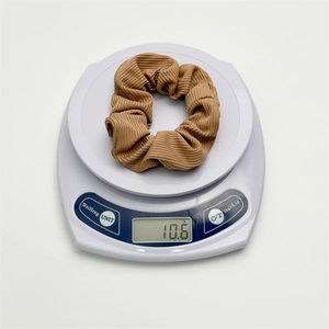Detail showing a brown ribbed fabric scrunchie on a scale weighing 10.6 grams accurately