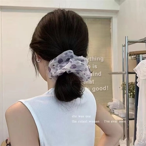 Dettaglio di un elastico per capelli in chiffon bianco a pois su una coda di cavallo