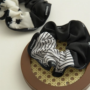 Close-up of navy style scrunchies featuring black and white floral patterns and CHANGE ribbon