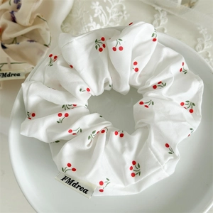 Floral scrunchie with red cherry print in a white ceramic dish, sweet aesthetic style