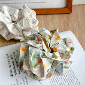 Close-up of floral print oversized chiffon scrunchies on a magazine and wooden desk