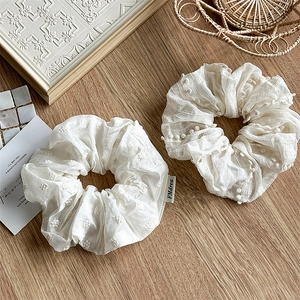 Set of two cream white fabric scrunchies with floral embroidery and wavy pom-pom edges