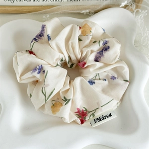 Detail view of floral fabric scrunchie with lavender print and woven brand label