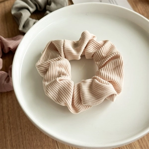 Detailed view of the ribbed fabric texture and elastic band of this apricot hair scrunchie