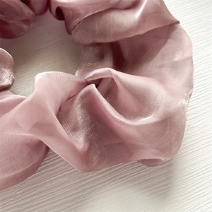 Vista macro di un elastico per capelli in organza viola con morbida trama a pieghe
