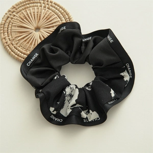 Detail showing high-quality black scrunchie with white 'CHANGE' text and abstract prints