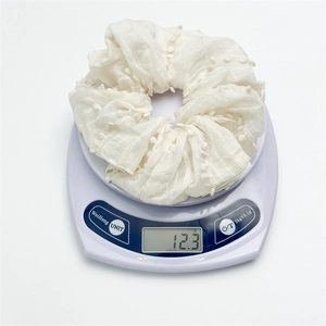 Detailed close-up showing light cream fabric hair scrunchie weighing 12.3g on a scale