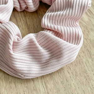 Detailed macro view of pink ribbed elastic scrunchie fabric on wooden background