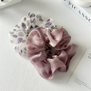 Dettaglio di elastici in seta viola e chiffon a pois su uno sfondo minimalista