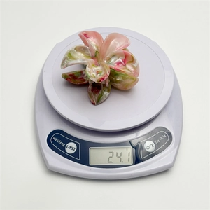 Pink and green flower hair claw clip on a digital scale weighing 24.1 grams