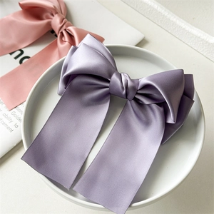 Détail d'un grand nœud papillon en satin lilas sur une assiette décorative en céramique