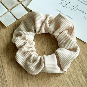 Close-up of beige ribbed scrunchie texture on a modern minimalist wooden background