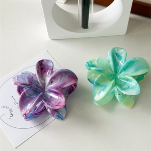 Detailed top view of large floral hair claws with purple and green marble texture