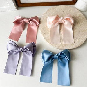 Détail de quatre barrettes nœuds en satin avec de longs rubans élégants en couleurs pastel