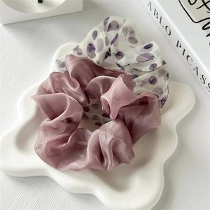 Elegante set di scrunchie in seta viola con pois bianchi su un vassoio di ceramica