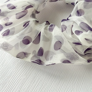Dettaglio macro dell'elastico in organza bianca con motivi romantici a pois viola