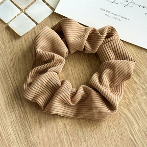 Detail of khaki ribbed fabric scrunchie with high elasticity texture on a wooden table