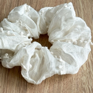 Elegant white chiffon hair scrunchie with soft pom-poms and textured stripe patterns