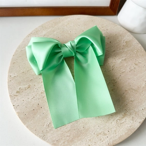 Gros plan d'une pince à cheveux en satin vert menthe avec rubans sur présentoir