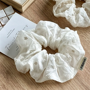 Detail of white daisy embroidery on soft cream fabric scrunchie with FMdrea label