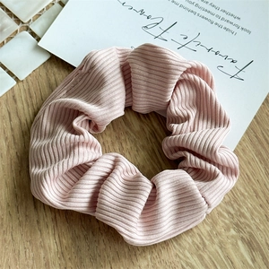Pink ribbed scrunchie with Morandi stripe texture on a minimalist wooden tabletop