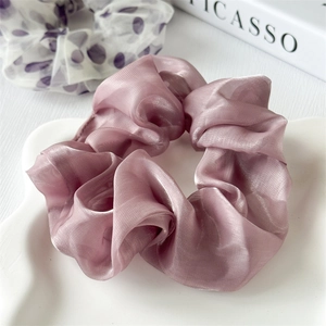 Dettaglio di un elastico per capelli in organza rosa antico e uno a pois viola