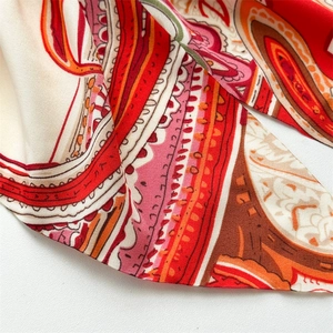 Macro view of paisley pattern silk scarf with vibrant red and orange vintage patterns