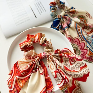 Close-up of vintage paisley pattern hair scrunchie with long ribbon on a white plate