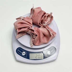Detailed view of a pink polka dot satin scrunchie weighing 20.8g on a digital scale