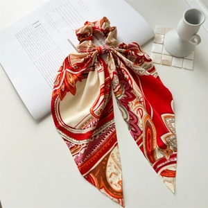 Detail of red and orange paisley pattern satin hair scrunchie with long ribbon tails