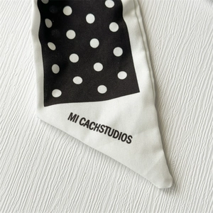 Détail de l'accessoire cheveux à nœud montrant les pois noirs et blancs et le tissu fin