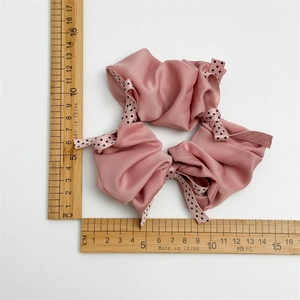 Set of three dusty pink satin polka dot bow scrunchies shown with measuring rulers