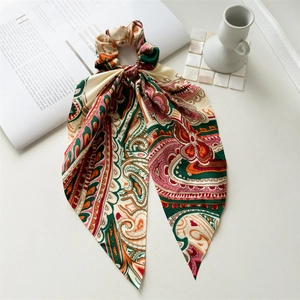 Detail of silk-like long ribbon scrunchie with bohemian paisley patterns and vintage colors