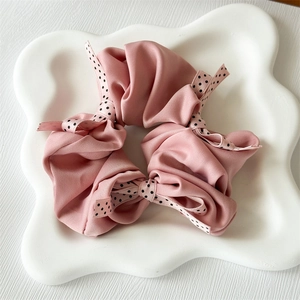 Detail of dusty pink satin scrunchie with black and white polka dot ribbon bows
