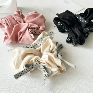Detailed close-up of large satin scrunchies with polka dot bows in pink, white, and black