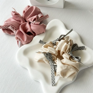 Satin polka dot bow scrunchies in pink and beige displayed on a decorative tray