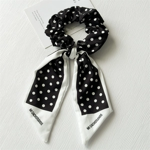 Détail d'un chouchou à pois en tissu satiné avec rubans et marquage de la marque