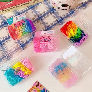 Close-up of colorful kids hair elastics stored in a clear rectangular plastic organizer box