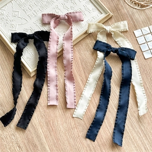 Detailed view of ruffled ribbon hair clips in black, pink, beige, and navy satin
