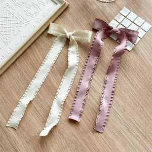 Detail of cream white and dusty pink pleated ribbon hair bows on a rustic wooden table
