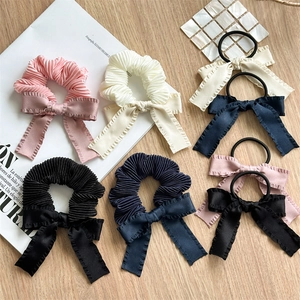 Close-up of pleated scrunchies and bow hair ties in assorted colors on wooden desk