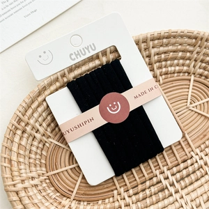 Detail of high-elastic black hair ties on a white card inside a woven basket decor
