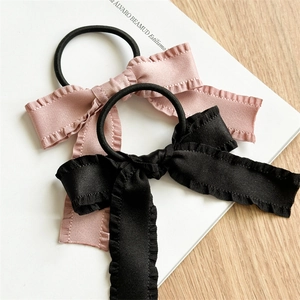 Detailed close-up of bow knot satin hair ties in pink and black colors with ruffled edges